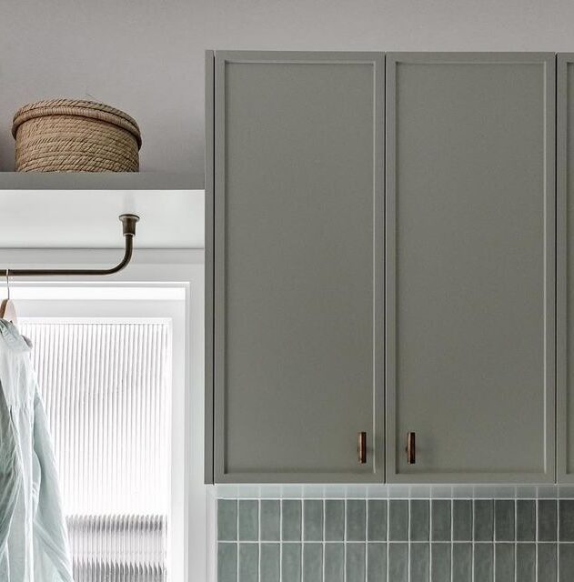 Laundry with green vinyl-wrapped overhead cupboards, tiled splashback, and a built-in hanging rail