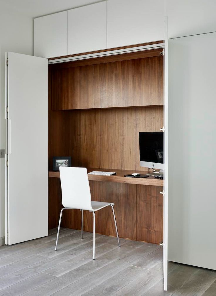 Compact home office concealed behind white bifold doors, featuring built-in desk and shelving